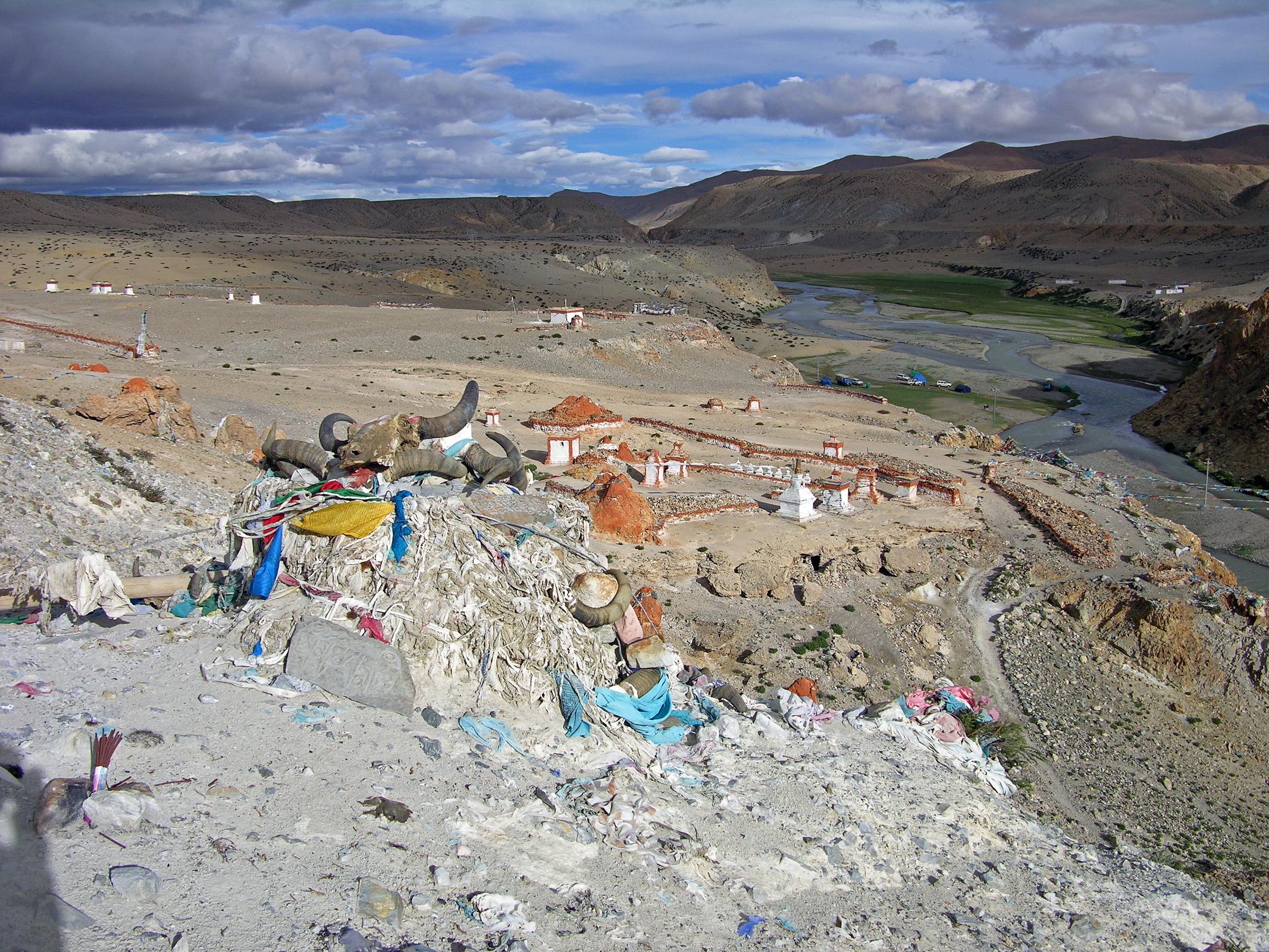 Tibet Kailash 06 Tirthapuri 11 View From Pass On Kora After the hot springs the trail climbs past a cremation area consecrated to Yeshe Tsogyal, and then reaches a miniature version of Kailash's Dlma La, marked with mani stones, prayer flags and a large collection of yak horns and skulls. To the left is the end of a recently constructed over 200m long mani wall, which points to the northeast directly towards Mount Kailas. The wall was the end result of a demon firing an arrow at the guru. He stopped the arrow's flight and transformed it into this wall.